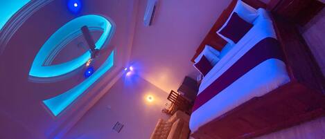 Une chambre à coucher moderne avec un grand lit, un canapé et un luminaire circulaire au plafond.