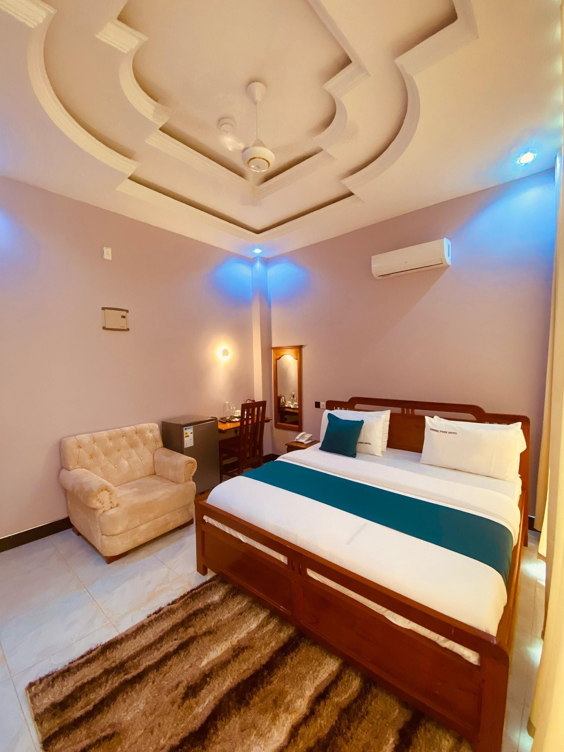 A bedroom with a bed, a sofa, a desk, and a mirror.