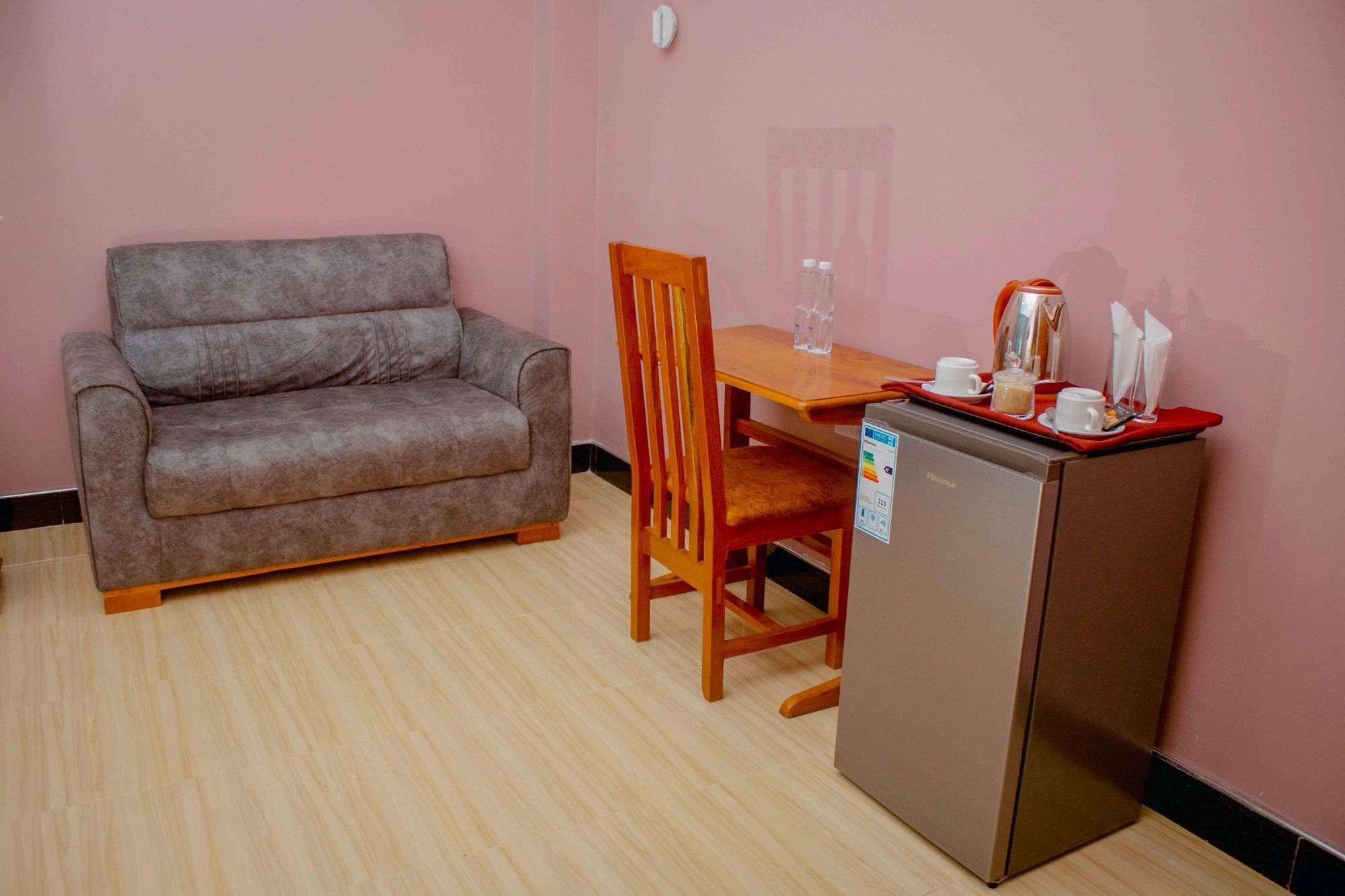 A compact room with a sofa, a wooden chair, a small table, and a refrigerator.