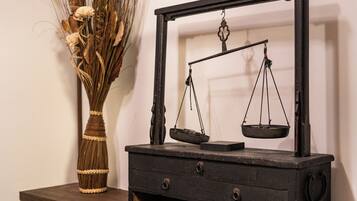 A vintage scale on a wooden table with a vase of dried flowers beside it.