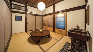 A traditional Japanese room with tatami flooring, a round wooden table, sliding doors, and a ceiling fan. - Aburaya Bettei (Beppu)