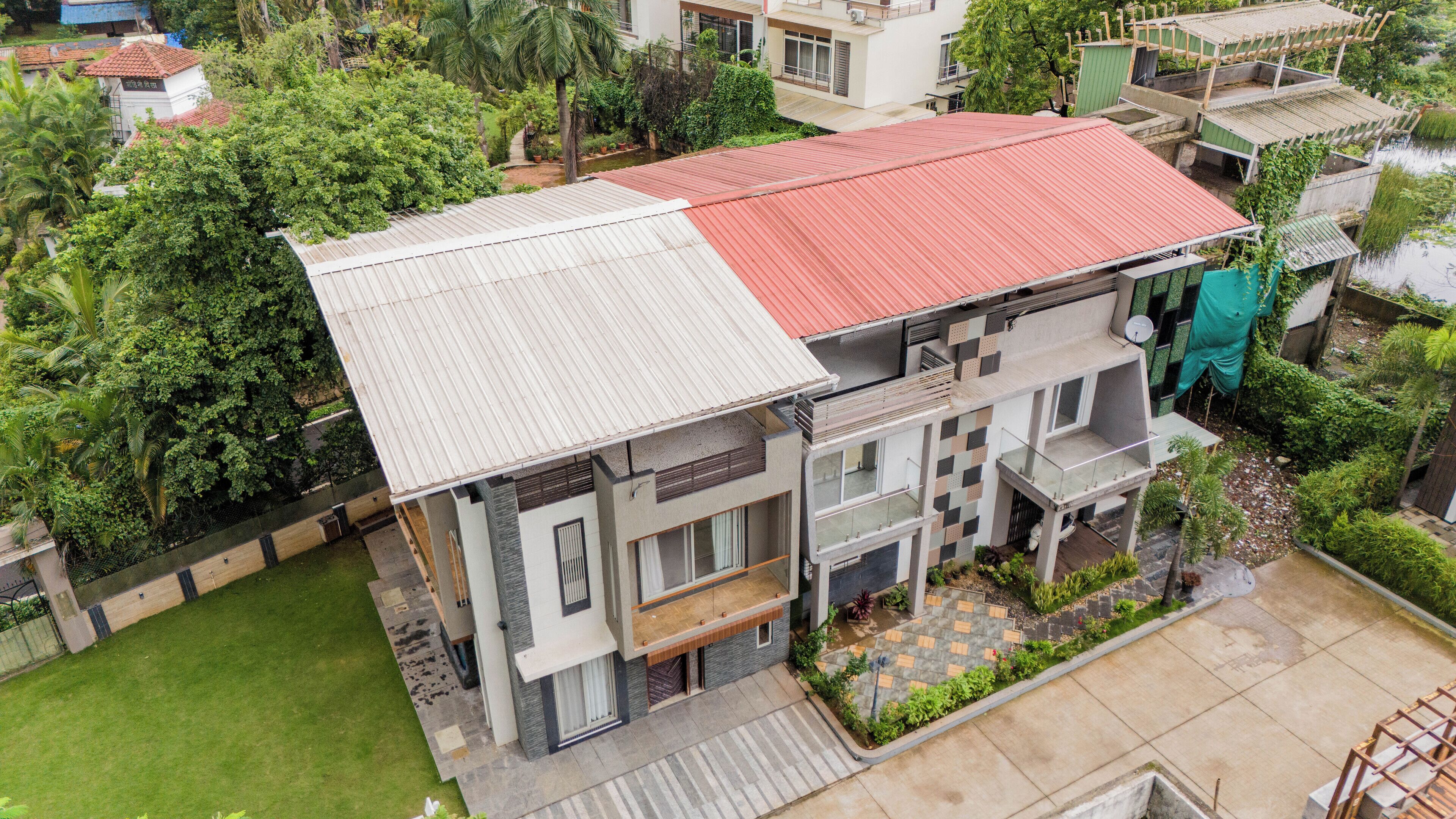 A multi-story residential building with a red roof, a balcony, and a garden area.
