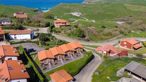 Uma área residencial à beira-mar, com casas, uma estrada e vista para o mar.