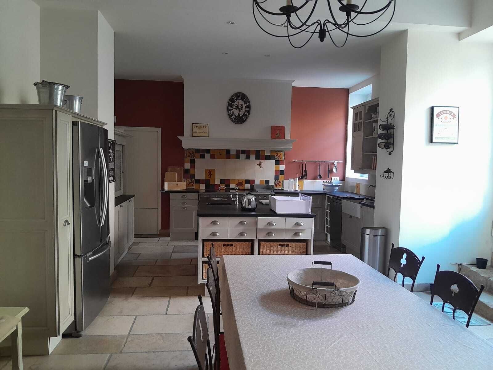 Een moderne keuken met een roestvrijstalen koelkast, een spoelbak en een eethoek met een tafel en stoelen.