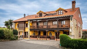 A two-story building with a yellow facade, a red-tiled roof, and a balcony.