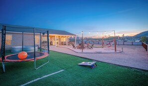 Un jardin avec un trampoline, un espace détente et un hamac.