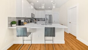 A modern kitchen with a large island, stainless steel appliances, and pendant lighting. - Heated Pool Oasis • Arcade + Games • Walk to Beach (St. Augustine)