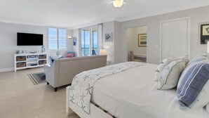 Un dormitorio con cama, televisor, sofá y balcón con vistas.