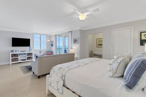 Un dormitorio con cama, televisor, sofá y balcón con vistas.