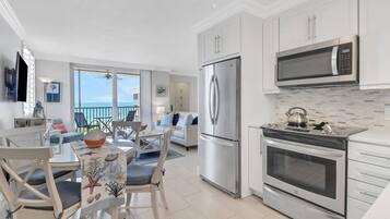 A modern kitchen with a refrigerator, microwave, and oven. There is a dining area with a table and chairs.
