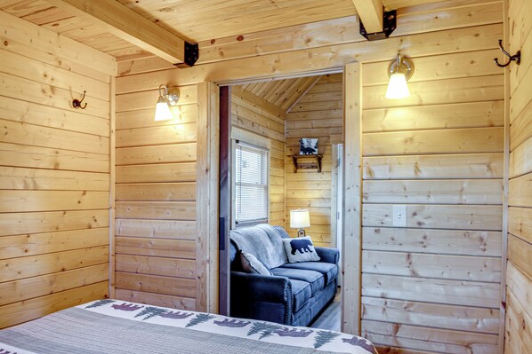 Ein Zimmer in einer Holzhütte mit einem Bett, einer Couch und einem Fenster.