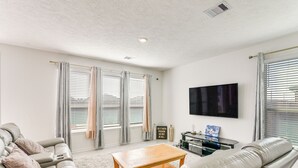 A modern living room with a beige sofa, a wooden coffee table, and a flat-screen TV mounted on the wall. - 11 Mi to Beach: La Marque Home w/ Patio! (La Marque)