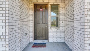 A white brick building with a brown door, a small window, and a doormat. - 11 Mi to Beach: La Marque Home w/ Patio! (La Marque)