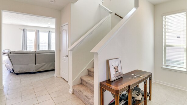 A living room with a beige sofa, a wooden console table, and a staircase with white railings. - 11 Mi to Beach: La Marque Home w/ Patio! (La Marque)