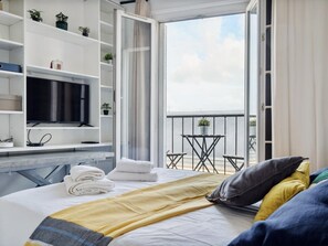 Una camera d'albergo con un letto, una TV, un balcone con tavolo e sedie e vista sull'acqua.
