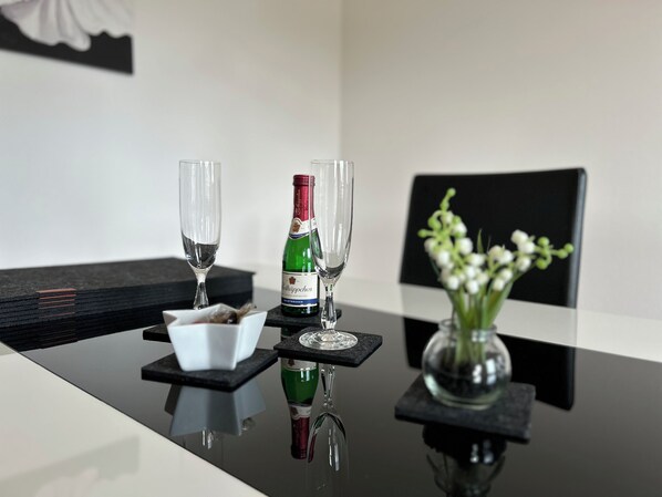 A table with two glasses, a bottle, and a bowl of fruit.
