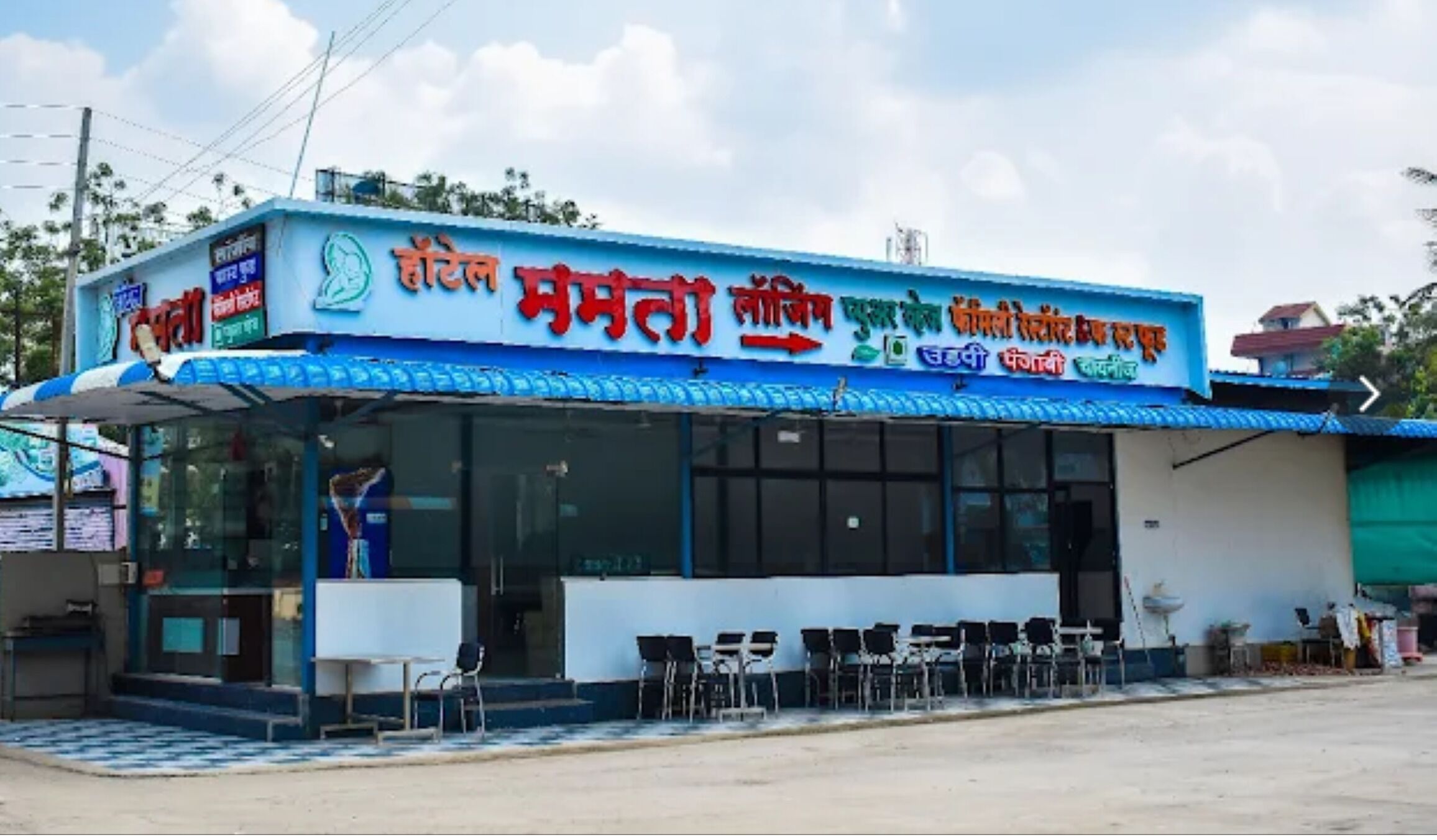 A two-story building with a blue and white facade, featuring a signboard with text in multiple languages.