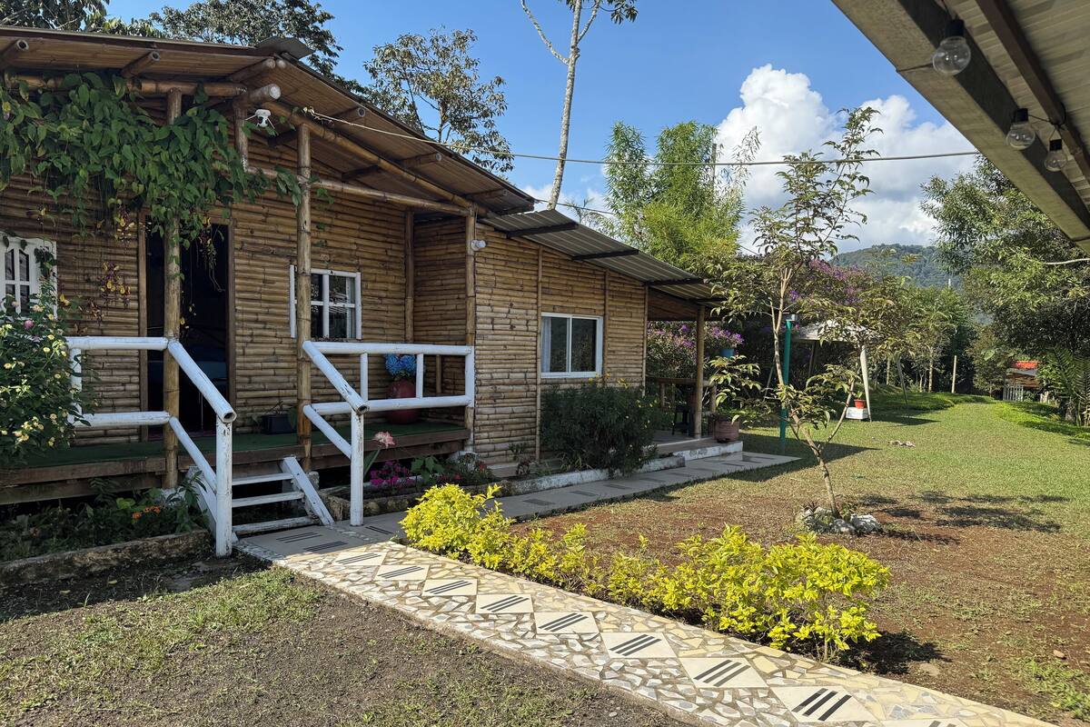 A wooden cabin with a porch, steps leading to the entrance, and a garden with yellow flowers.