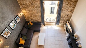 A modern living room with a stone wall, a sofa with cushions, a coffee table, and a TV.