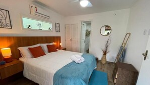 A bedroom with a bed, bedside table, lamp, and a ceiling fan. - Pousada alto das arvores (Buzios)
