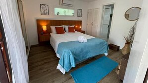A bedroom with a bed, bedside tables, a ceiling fan, and a window. - Pousada alto das arvores (Buzios)