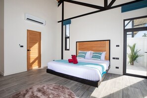 A modern bedroom with a wooden bed, a fluffy rug, and a view of the outdoors. - New 19m Eco Pool Villa Sunset Garden 10 (Rawai)