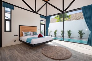 A modern bedroom with a floating bed, a large window with a view of a swimming pool, and a round rug on the floor. - New 19m Eco Pool Villa Sunset Garden 10 (Rawai)