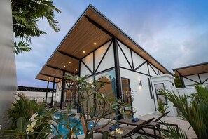 A modern building with a pool, surrounded by tropical plants and furniture. - New 19m Eco Pool Villa Sunset Garden 10 (Rawai)