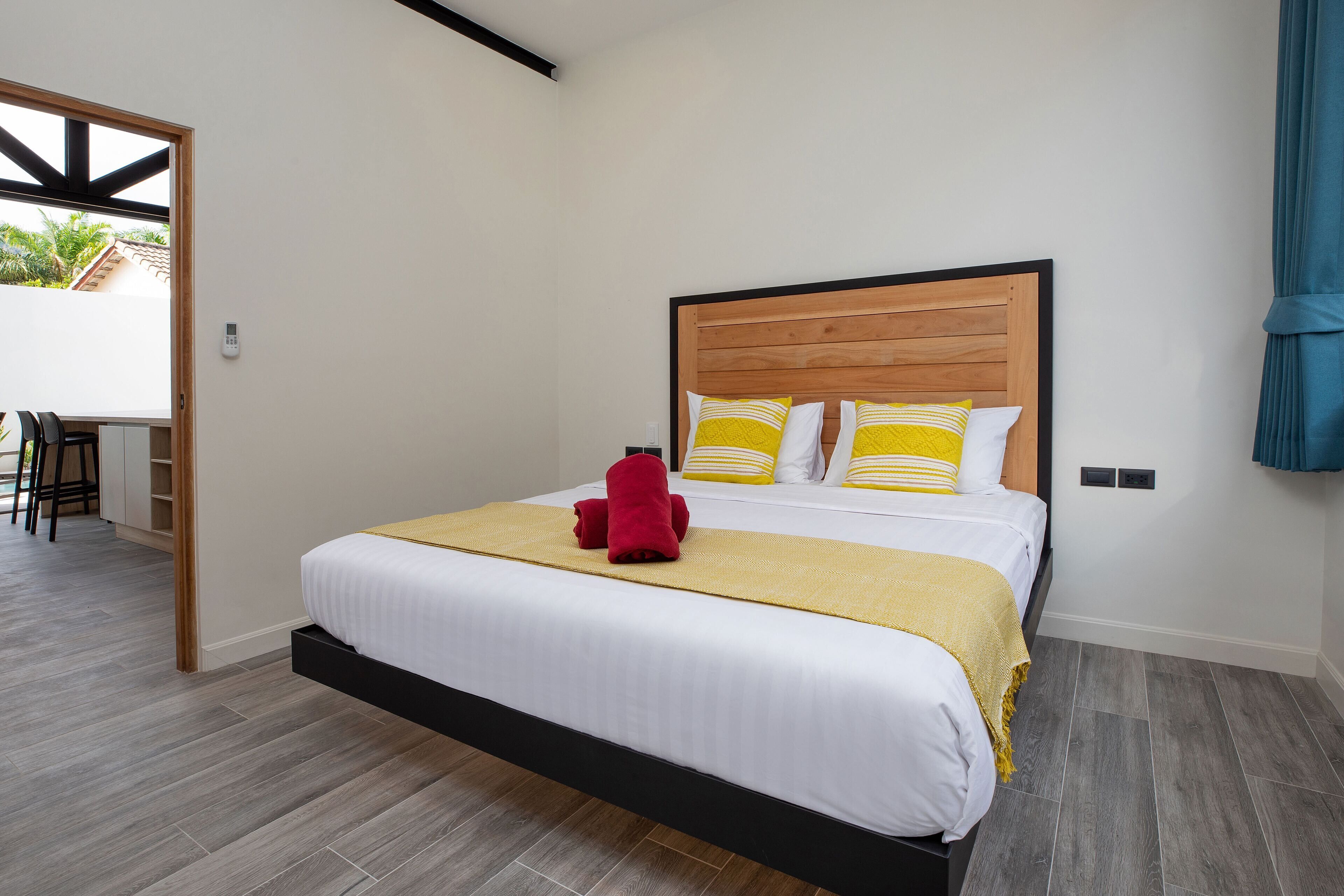 A neatly made bed with a wooden headboard, white bedding, and a yellow throw blanket.