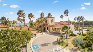 A hotel with a central courtyard, palm trees, and a view of the ocean.