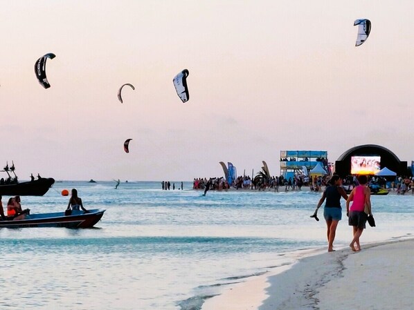 Une plage avec des gens, des bateaux et des cerfs-volants.