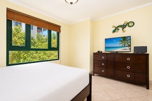 Een hotelkamer met een bed, een dressoir, een televisietoestel en een raam met uitzicht op groen.