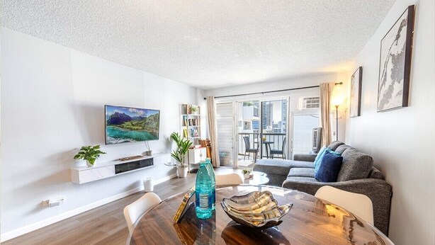 Ein modernes Wohnzimmer mit einem runden Holztisch, einer Couch, einem Fernseher und einem Balkon mit Blick auf die Stadt.