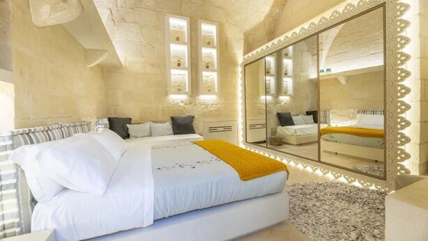 Ein Schlafzimmer mit einem großen Bett, einem Spiegel und einer Steinwand.