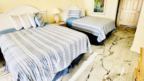 Une chambre d’hôtel avec deux lits, un sol en marbre, un tableau au mur et une porte donnant sur une autre pièce.