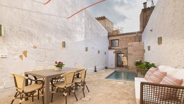 A patio with a table and chairs, a small pool, and a sofa.