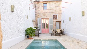 A pool area with a tiled floor, a potted plant, and outdoor furniture.