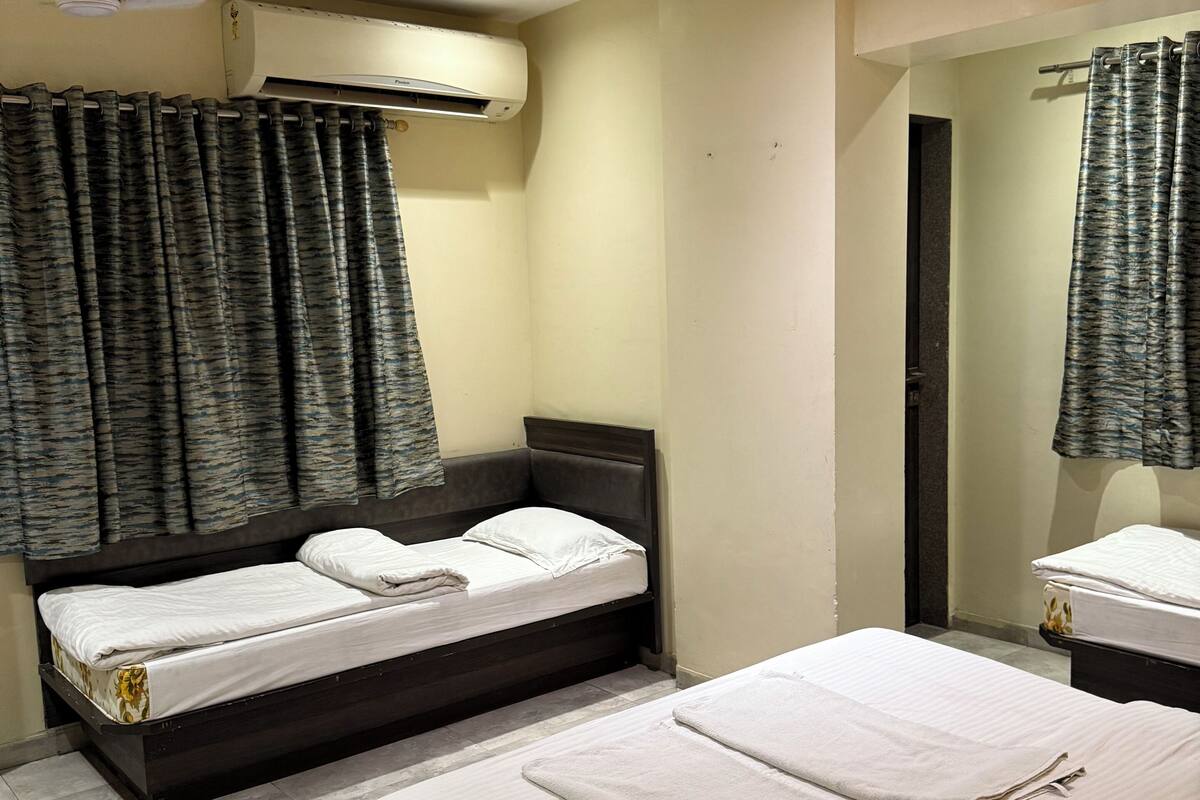 Ein Hotelzimmer mit zwei Betten, einem Deckenventilator, einer Klimaanlage und einem Badezimmer mit Duschvorhang.