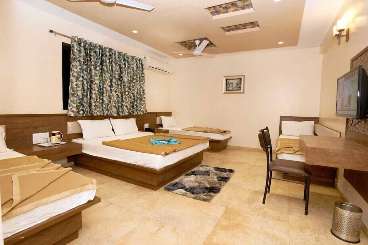 Ein Hotelzimmer mit zwei Betten, einem Schreibtisch, einem Stuhl, einem Fernseher und einem Deckenventilator.