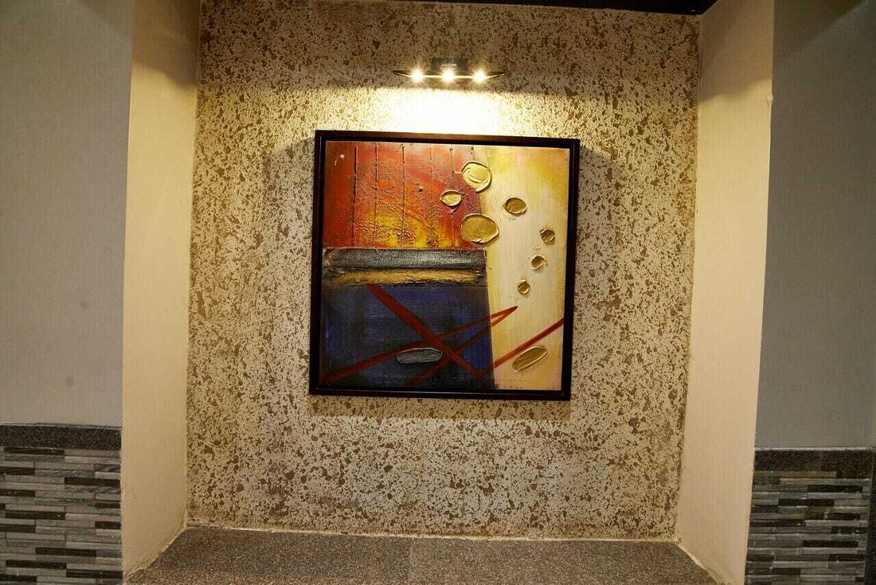 A framed abstract painting on a textured wall.
