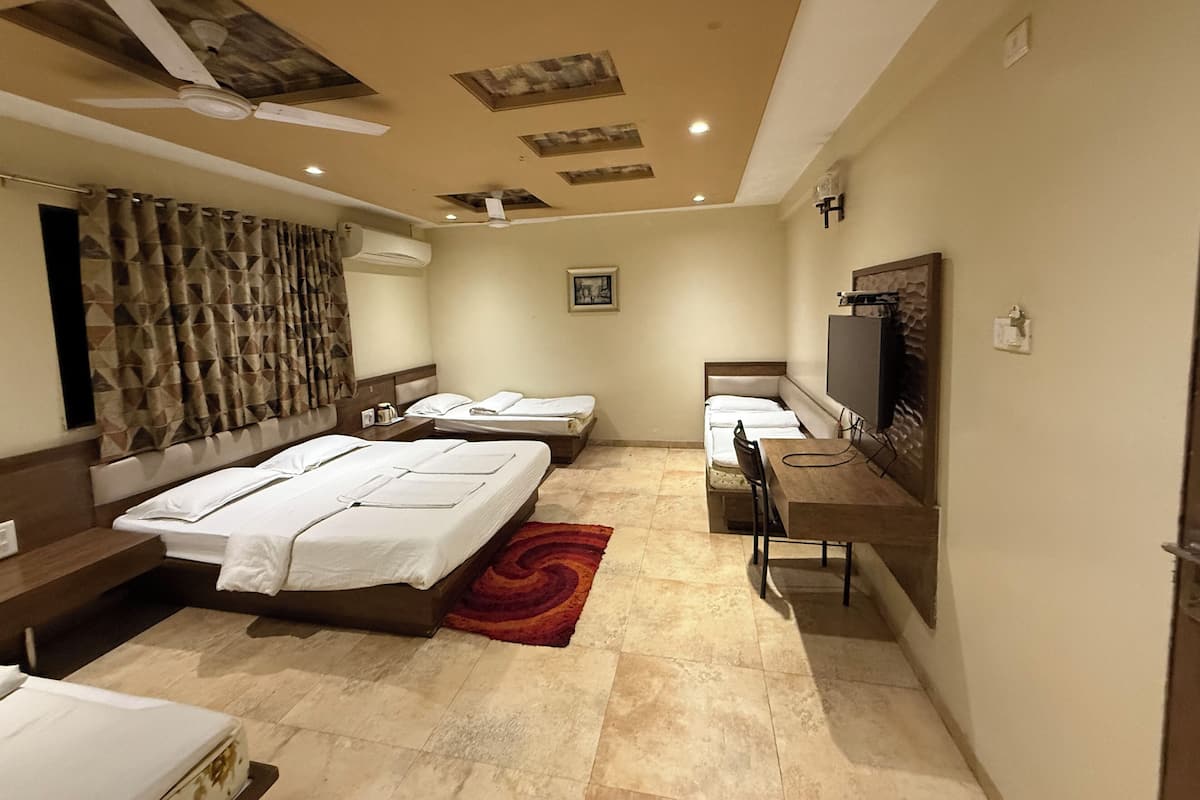 Ein Hotelzimmer mit zwei Betten, einem Schreibtisch, einem Fernseher und einem Deckenventilator.