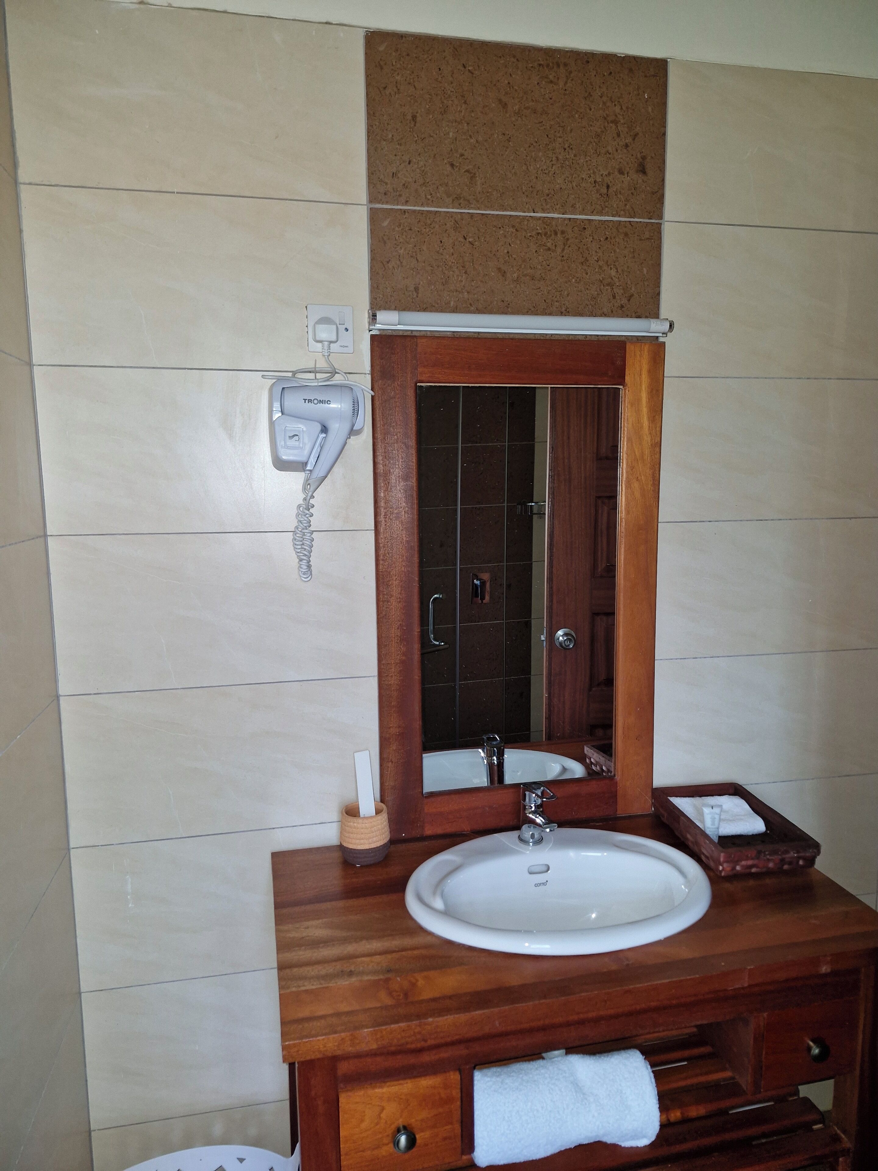 Une salle de bain avec un meuble-lavabo en bois, un lavabo blanc, un miroir et un porte-serviettes.