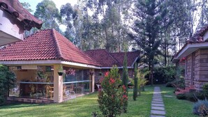 A house with a tiled roof, a glass door, and a garden with a pathway. - OD KIDI COTTAGES  (Migori)