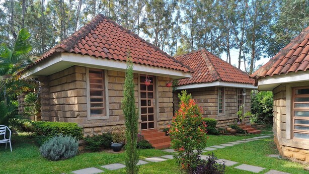 A stone cottage with a tiled roof, a small garden with a pathway, and a potted plant. - OD KIDI COTTAGES  (Migori)