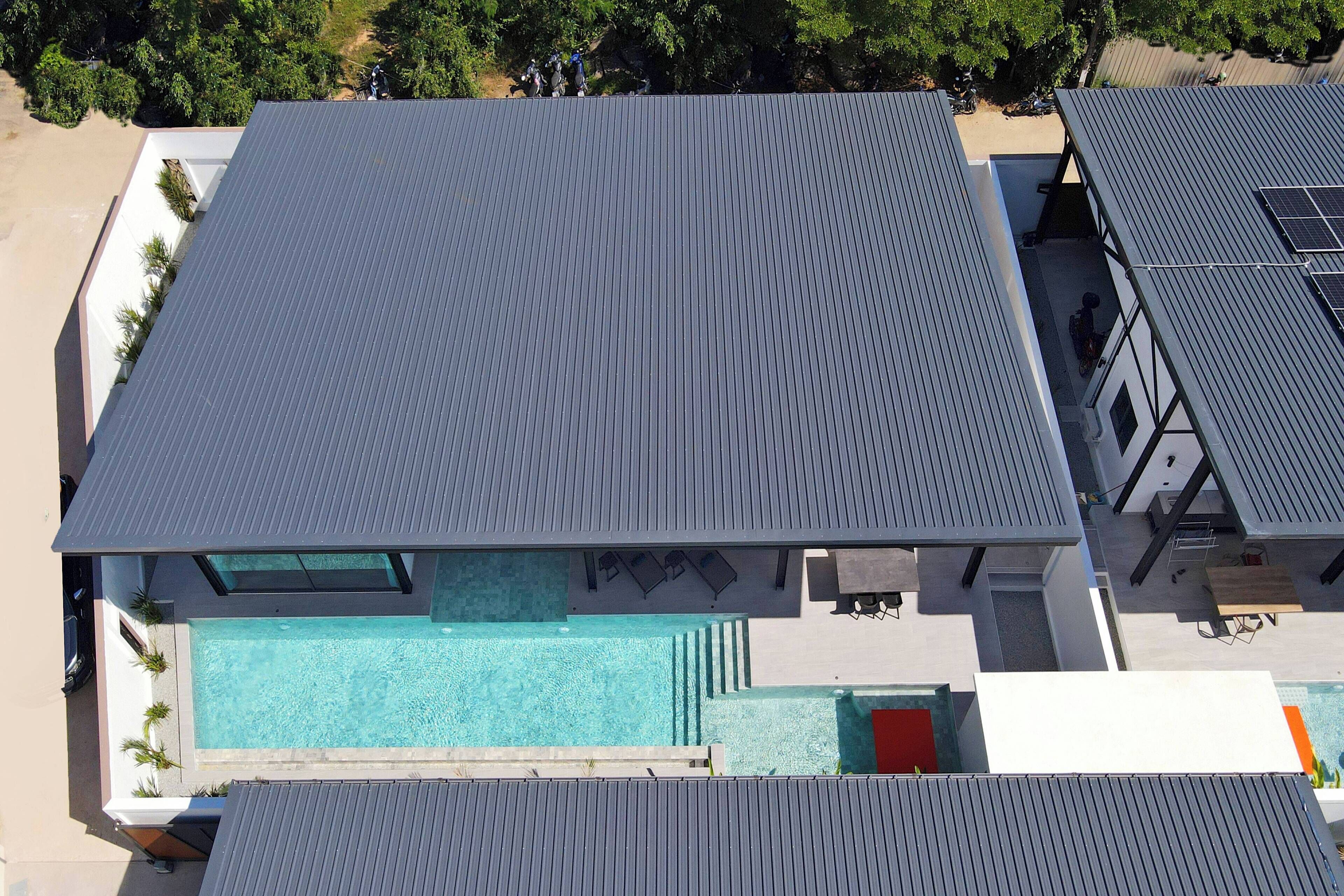 An aerial view of a modern building with a rooftop pool and a covered patio area.