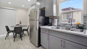 Een moderne keuken met roestvrijstalen apparatuur, een eethoek met zwarte stoelen en een raam dat natuurlijk licht binnenlaat.
