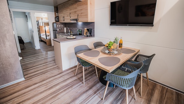 A modern kitchen with wooden cabinets, a built-in oven, and a flat-screen TV mounted on the wall. - Lake Serenity Premium Mobile Homes With Thermal Riviera Tickets (Brežice)