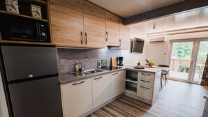 A modern kitchen with wooden cabinets, a stainless steel refrigerator, and a built-in microwave. - Lake Serenity Premium Mobile Homes With Thermal Riviera Tickets (Brežice)