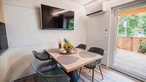 A modern dining area with a wooden table, black chairs, and a fruit bowl. - Lake Serenity Premium Mobile Homes With Thermal Riviera Tickets (Brežice)