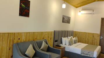 A room with a wooden ceiling, a bed, a sofa, a small table, and a wall-mounted air conditioner.